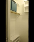 Tiny closet, her side, with large cubbie spaces and three-tiered shoe shelf